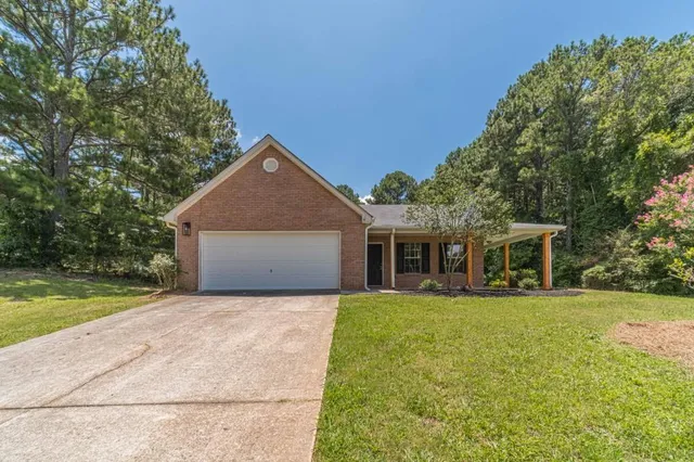 a front view of house with yard and trees in the background