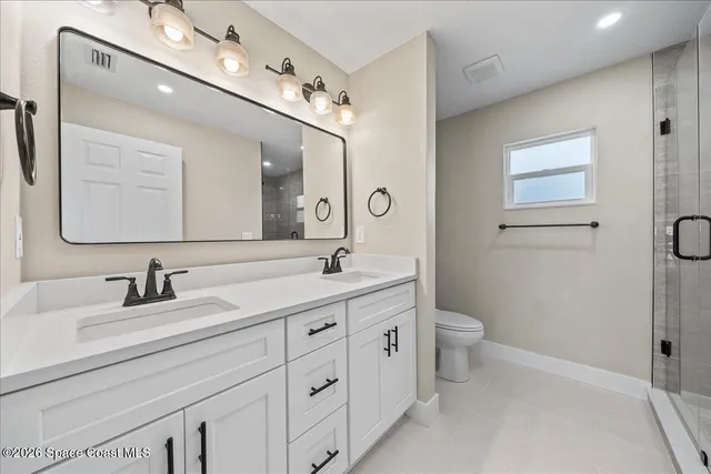 a bathroom with a toilet a double vanity sink and a mirror