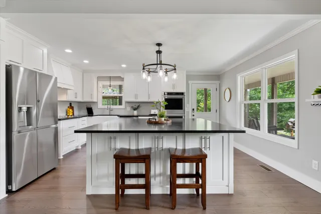 a kitchen with stainless steel appliances granite countertop wooden floors and white cabinets