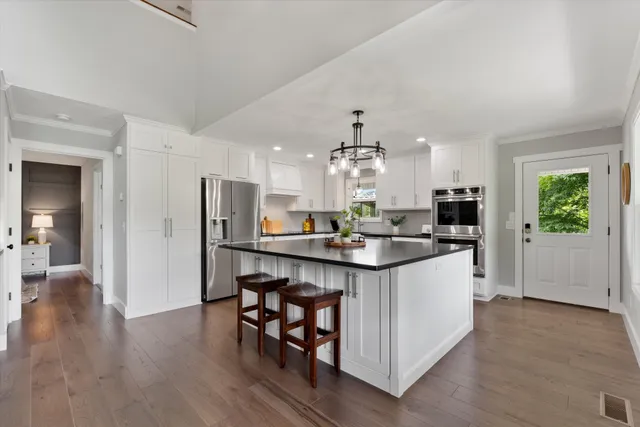 a kitchen with stainless steel appliances a kitchen island a stove a table and chairs in it