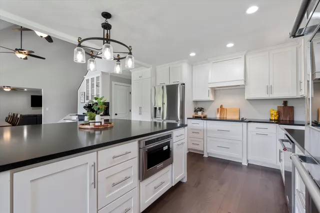 a kitchen with granite countertop white cabinets white appliances and sink