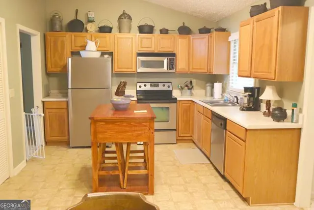 a kitchen with stainless steel appliances granite countertop a refrigerator a stove and a sink