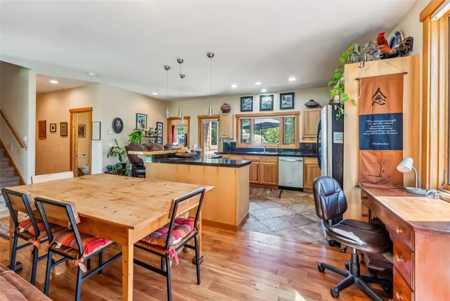 a dining room with stainless steel appliances kitchen island granite countertop a dining table chairs and a refrigerator