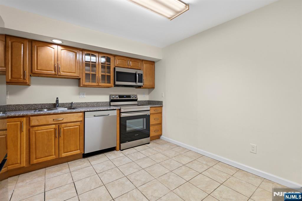 319 Gorge Road, Unit 6 Cliffside Park, NJ 07010 - Photo 8 of 24 a kitchen with stainless steel appliances granite countertop a stove a sink and a microwave