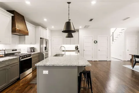 a kitchen with granite countertop a stove a sink and a refrigerator