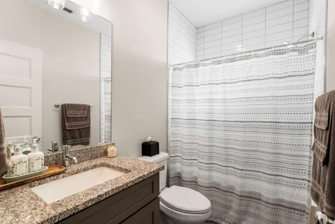 a bathroom with a granite countertop toilet sink and mirror