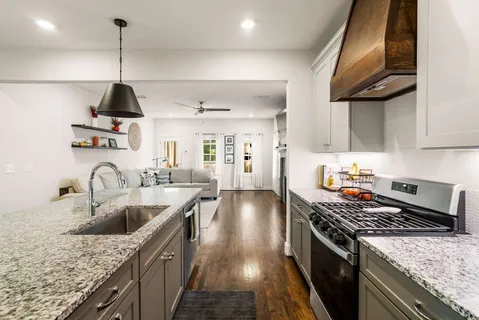 a kitchen with stainless steel appliances granite countertop a sink a stove and a wooden floors