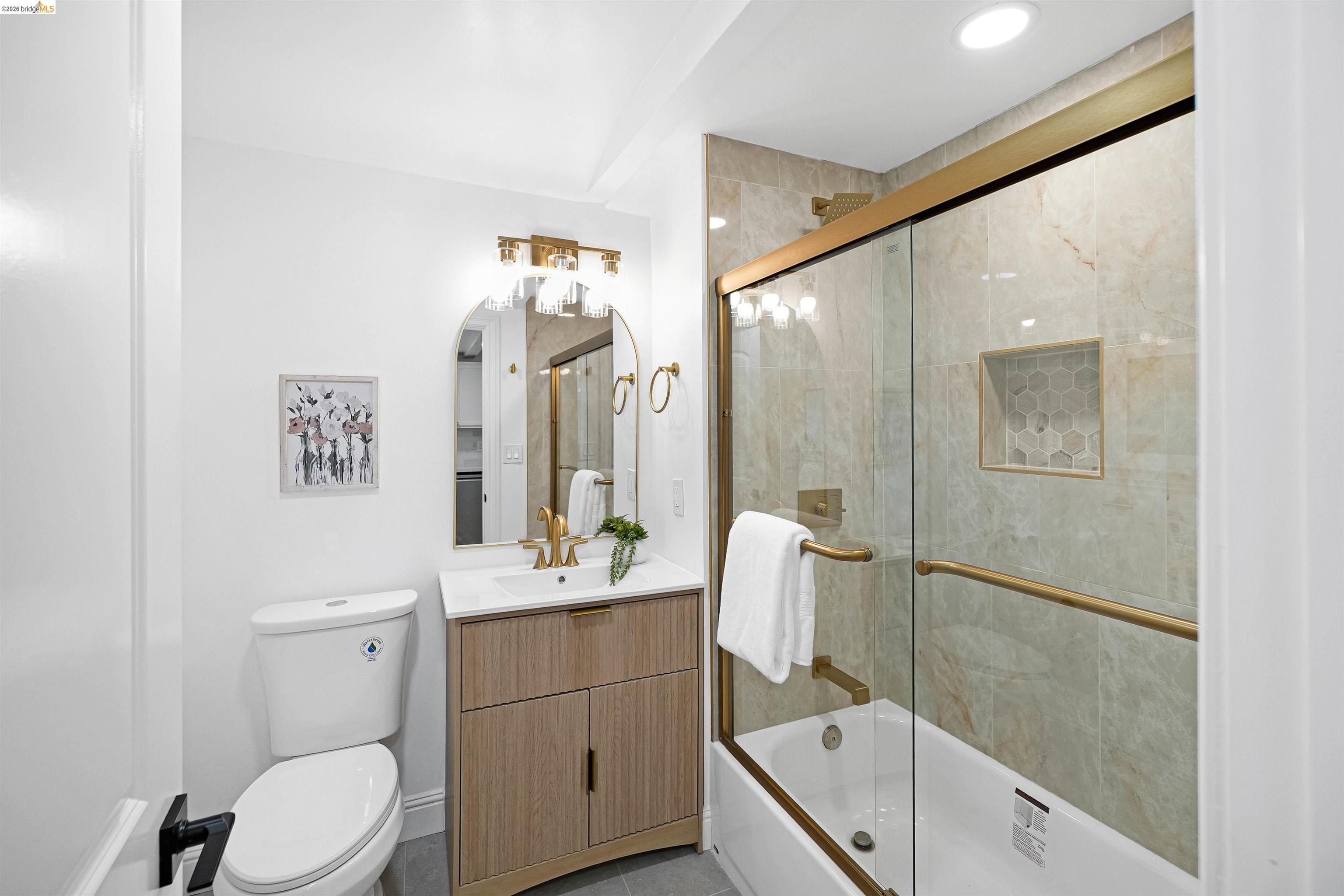 1812 Woolsey Street Berkeley, CA 94703 - Photo 15 of 48 Bathroom featuring a shower-tub combination with gold-finish sliding glass doors, a built-in shower niche with hexagonal tile, and large format wall tiling