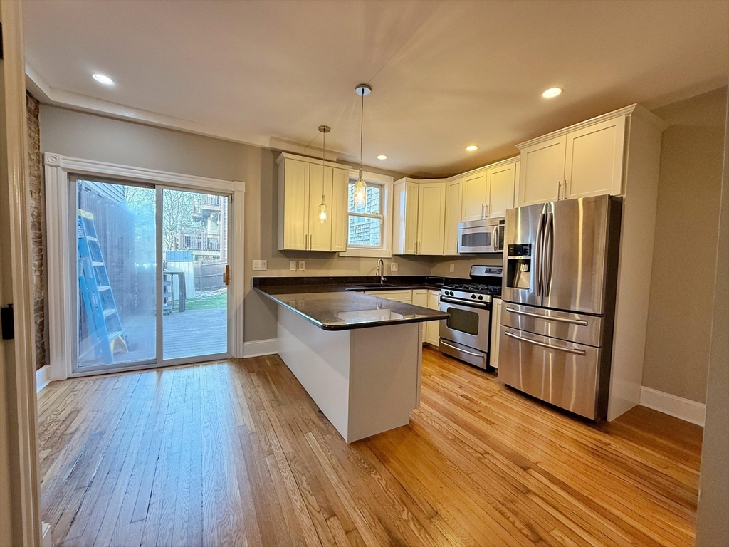 32 Covington Street, Unit SF Boston, MA 02127 - Photo 5 of 27 a kitchen with stainless steel appliances a refrigerator a sink dishwasher a stove and white countertops with wooden floor