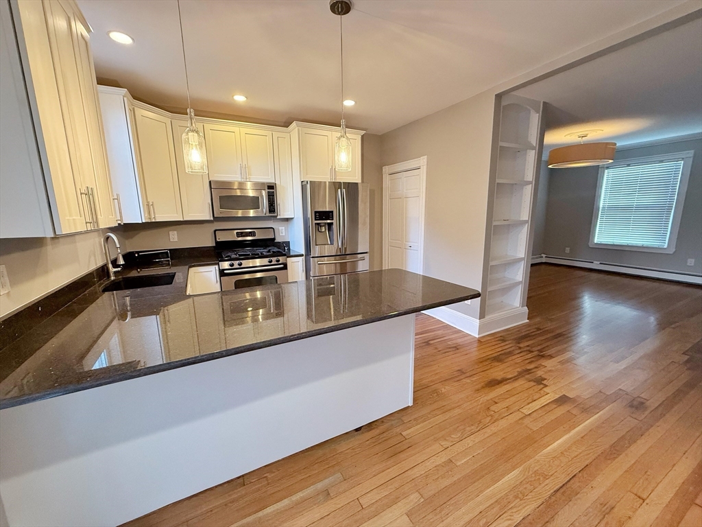 32 Covington Street, Unit SF Boston, MA 02127 - Photo 7 of 27 a kitchen with stainless steel appliances granite countertop a sink a stove and a wooden floors