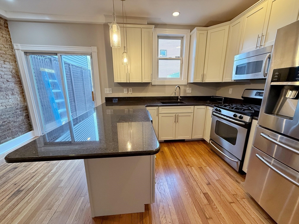 32 Covington Street, Unit SF Boston, MA 02127 - Photo 8 of 27 a kitchen with stainless steel appliances granite countertop a stove a sink and a microwave