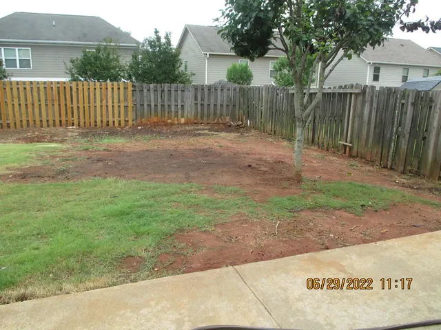 a backyard of a house with a bench and trees