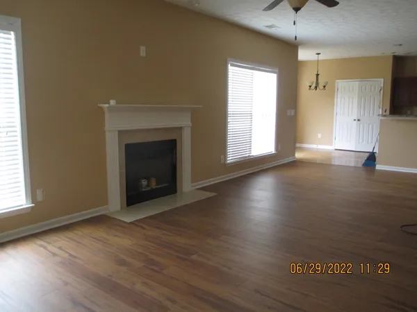 an empty room with wooden floor fireplace and windows
