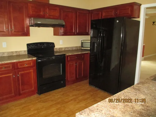 a kitchen with granite countertop wooden cabinets and refrigerator