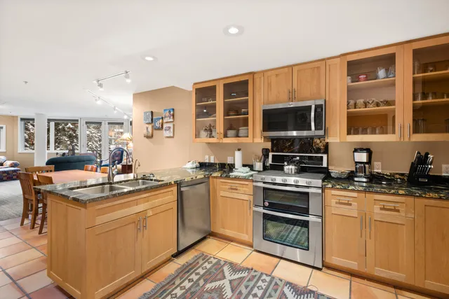 a kitchen with stainless steel appliances granite countertop a stove top oven a sink dishwasher and white cabinets with wooden floor