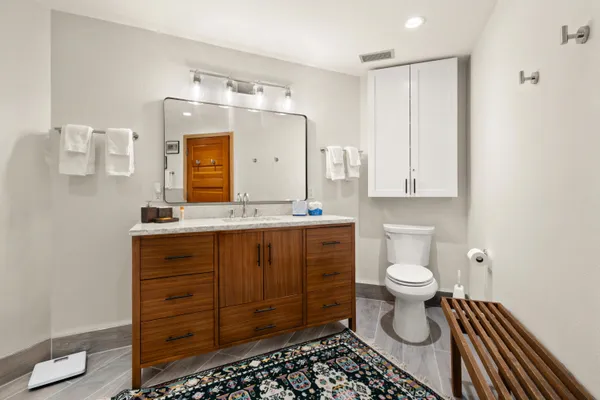 a bathroom with a granite countertop toilet sink and mirror