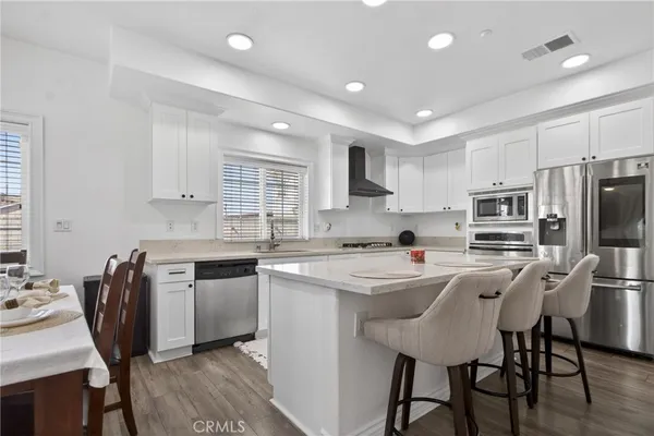 a kitchen with stainless steel appliances a table chairs refrigerator and microwave