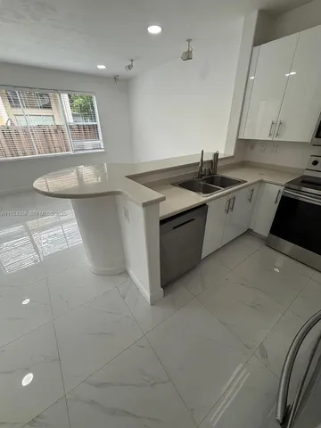 a kitchen with a refrigerator a sink a stove and white cabinets