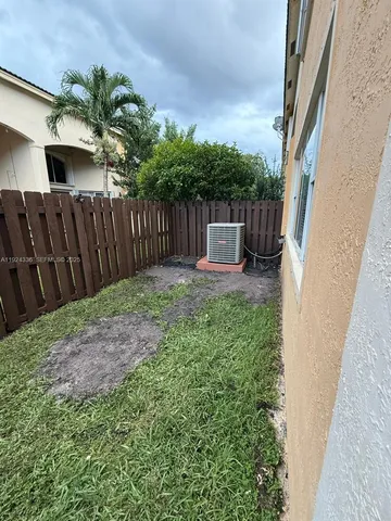 a view of a backyard with wooden fence and a bench