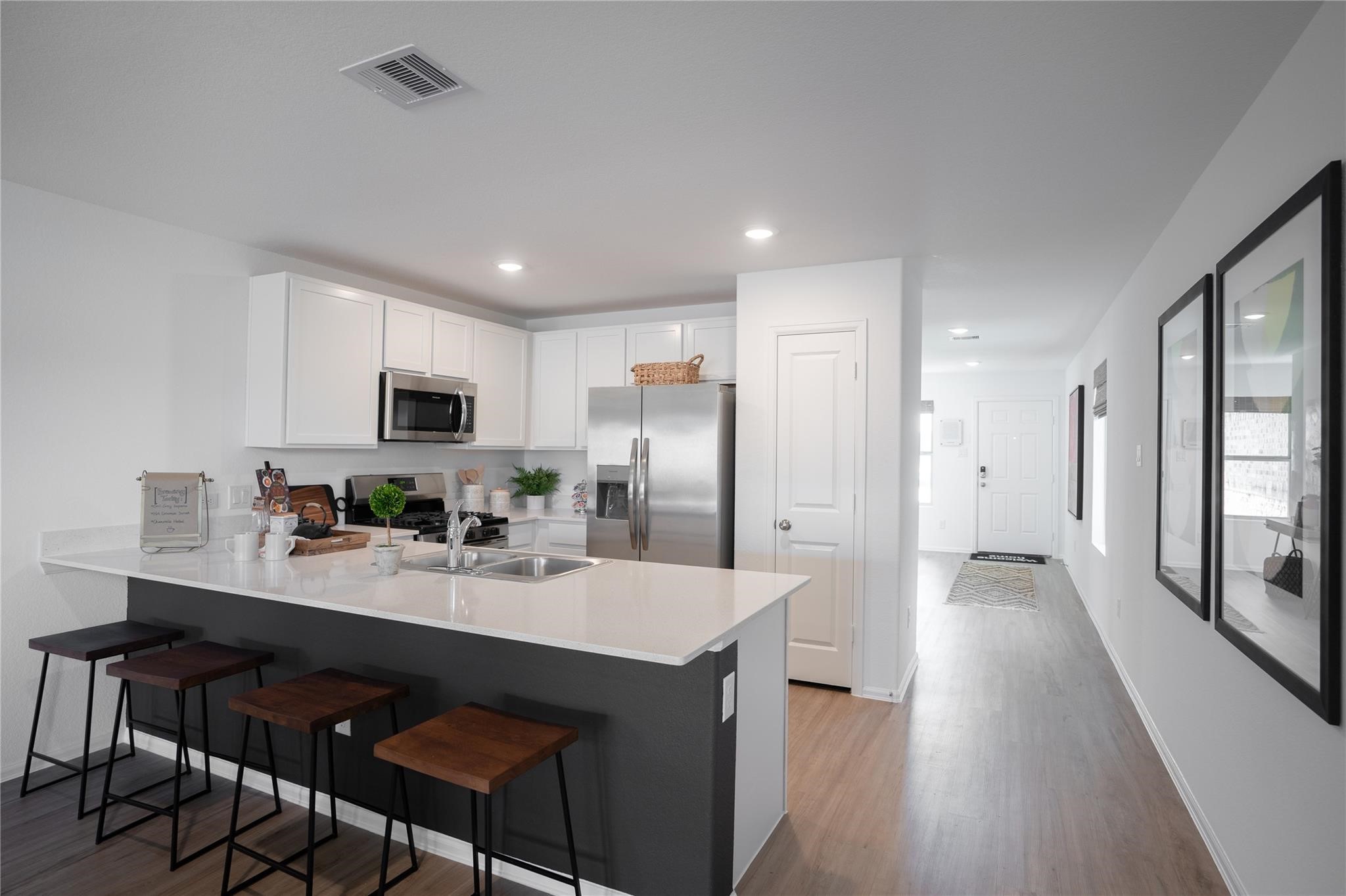 2935 Summer Breeze Way Angleton, TX 77515 - Photo 17 of 25 a kitchen with stainless steel appliances kitchen island granite countertop a refrigerator a sink dishwasher and white cabinets with wooden floor