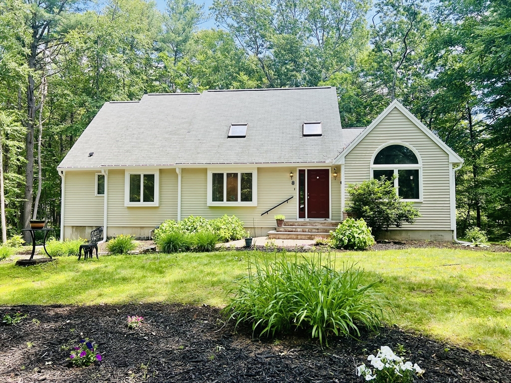 a front view of a house with garden and trees