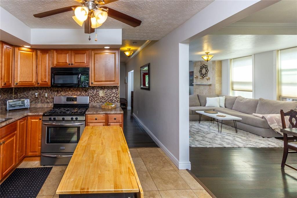 2114 Hampton Street Pittsburgh, PA 15218 - Photo 12 of 28 a kitchen with stainless steel appliances granite countertop a stove top oven a sink dishwasher a dining table and chairs with wooden floor