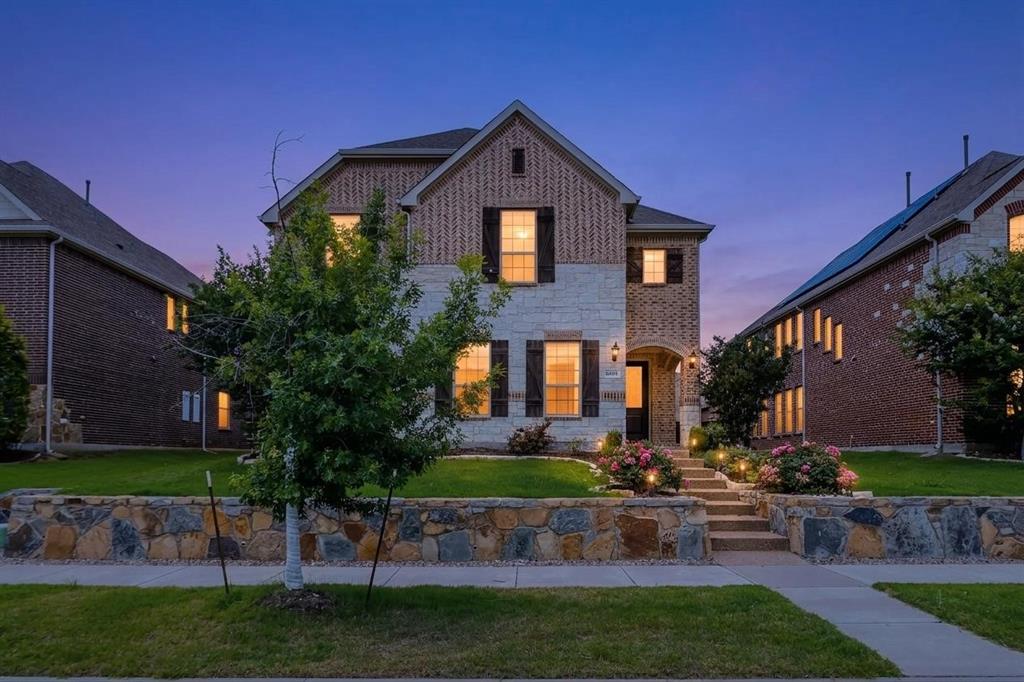 Brick and stone facade residence featuring a multi-level front yard with stone retaining walls