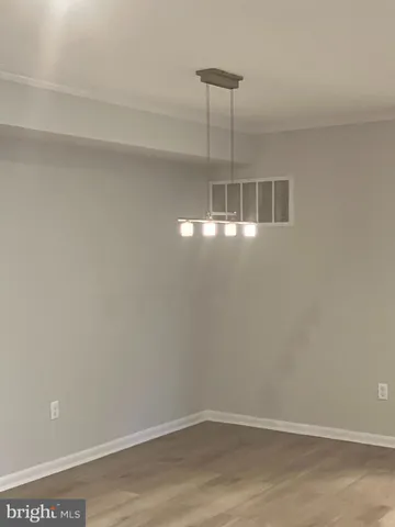 a room with a chandelier fan and wooden floor