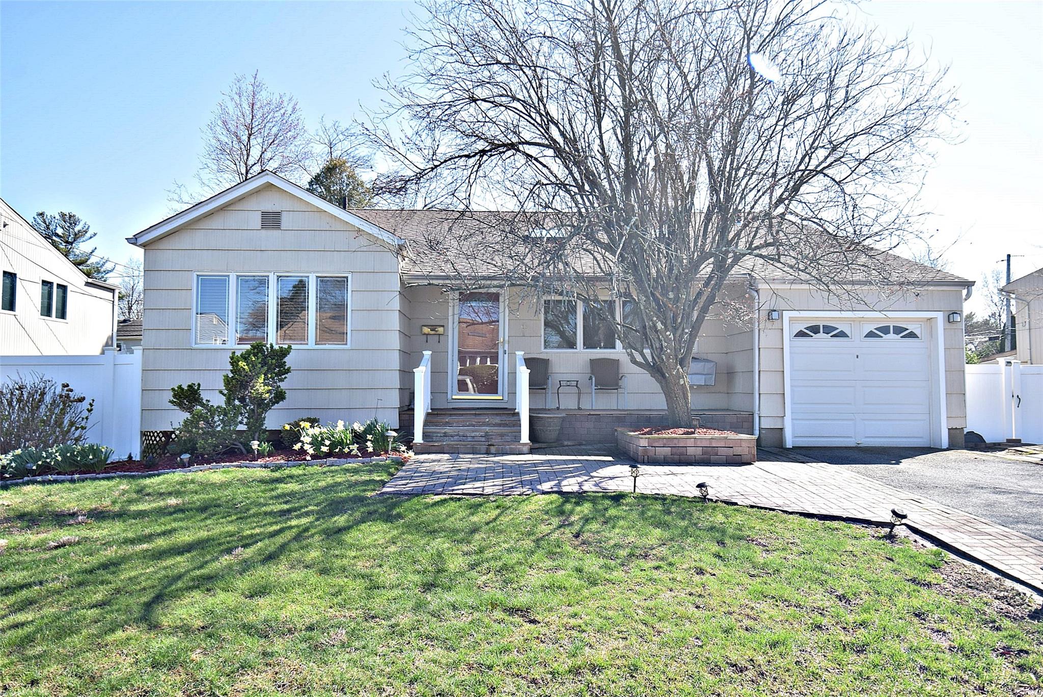 Ranch-style house featuring an attached garage, fence, driveway, and a front yard