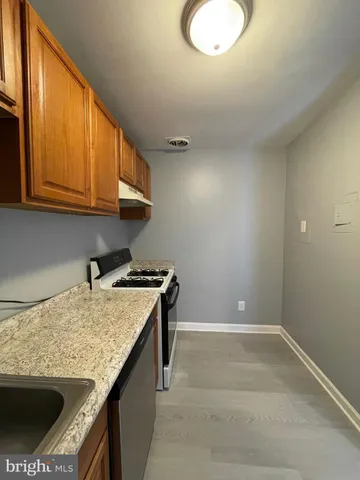 a kitchen with granite countertop wood cabinets stainless steel appliances and a sink