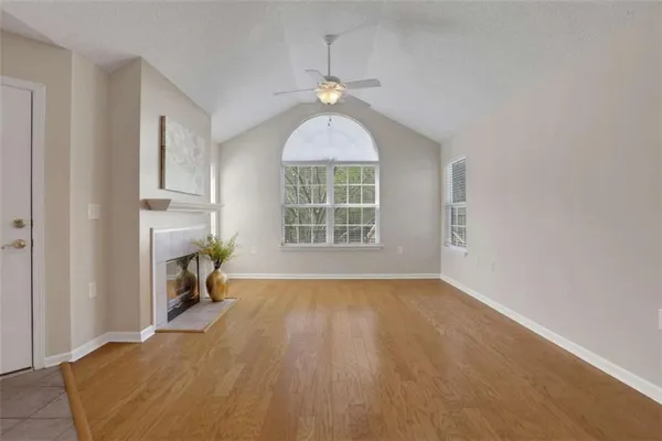 an empty room with windows fireplace and wooden floor