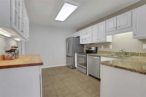 a kitchen with granite countertop white cabinets and stainless steel appliances