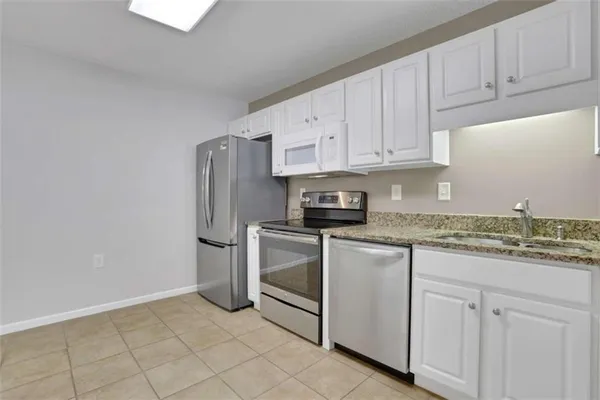 a kitchen with granite countertop white cabinets and sink