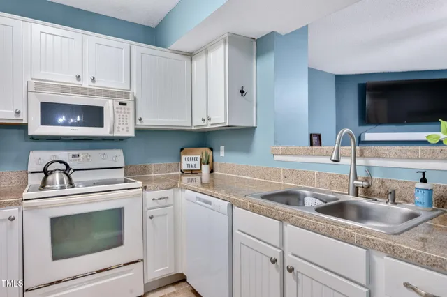 a kitchen with granite countertop a sink white cabinets and stainless steel appliances