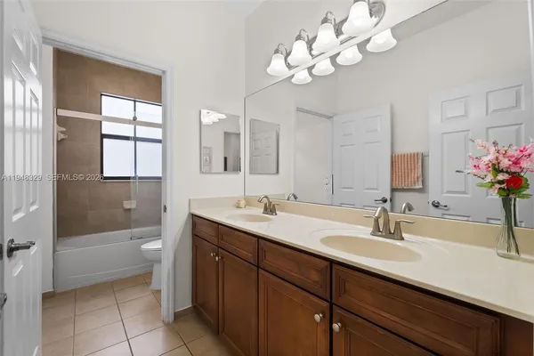 a bathroom with a tub a sink double vanity and a mirror