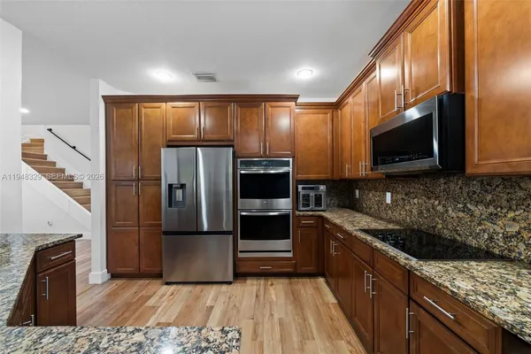 a kitchen with granite countertop a refrigerator and microwave