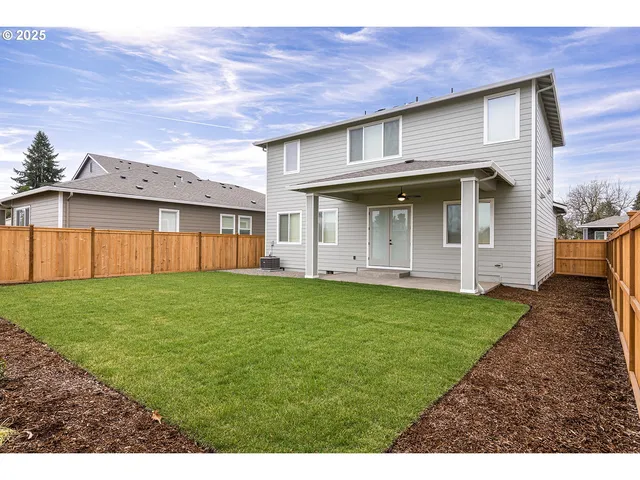 a view of a backyard with plants and large trees