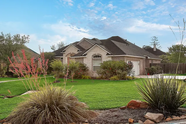 a view of a house with a big yard plants and large trees
