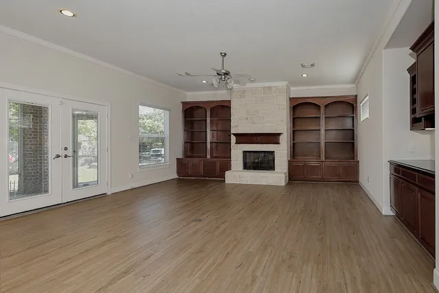 an empty room with wooden floor fireplace and windows