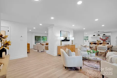 a living room with furniture and a dining table with wooden floor