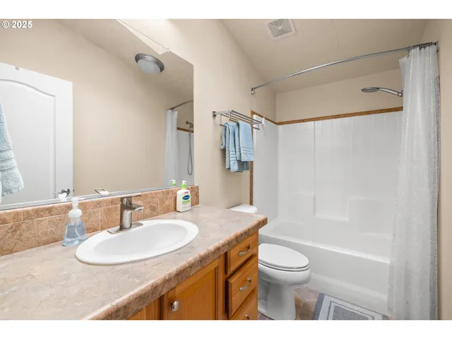 a bathroom with a granite countertop sink toilet a mirror and shower