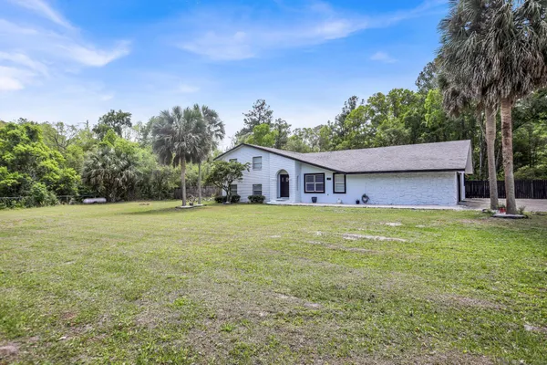 a view of a house with a yard and palm trees