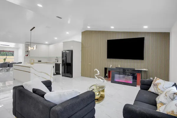 a large white kitchen with a large counter top space a sink stainless steel appliances and cabinets