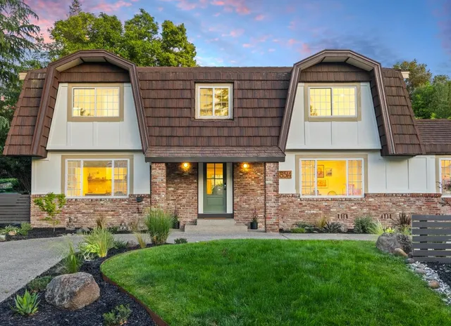 a view of a brick house with a large windows and a yard in front of it