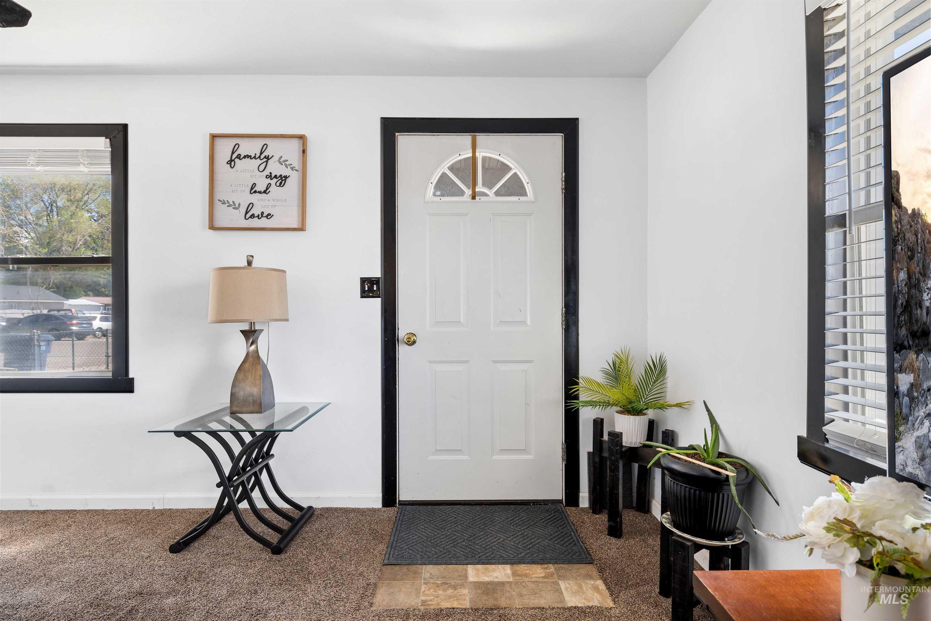 102 East 6th Street Rupert, ID 83350 - Photo 4 of 27 Entryway featuring a white paneled door with a half-moon glass insert, contrasting black trim, and light-colored walls