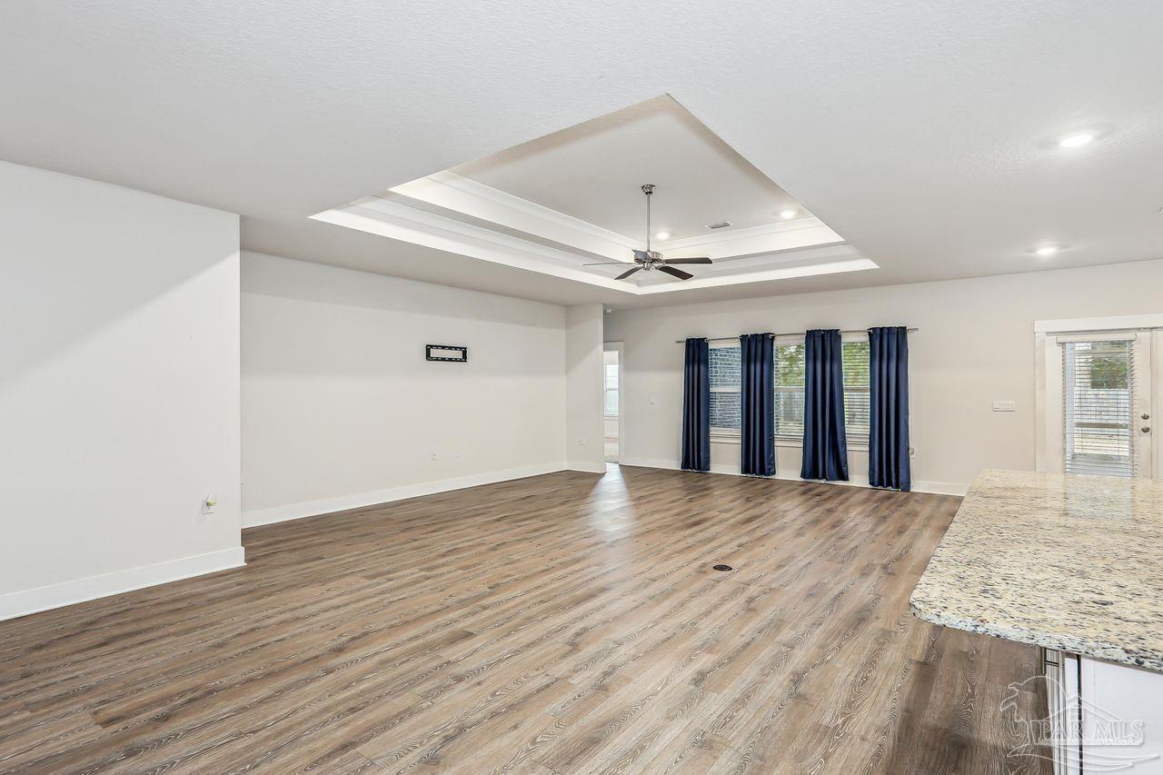5665 Blake Lane Pace, FL 32571 - Photo 13 of 44 a view of an empty room with wooden floor and a ceiling fan