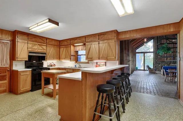 a kitchen with stainless steel appliances granite countertop a stove a sink dishwasher and a refrigerator with wooden cabinets