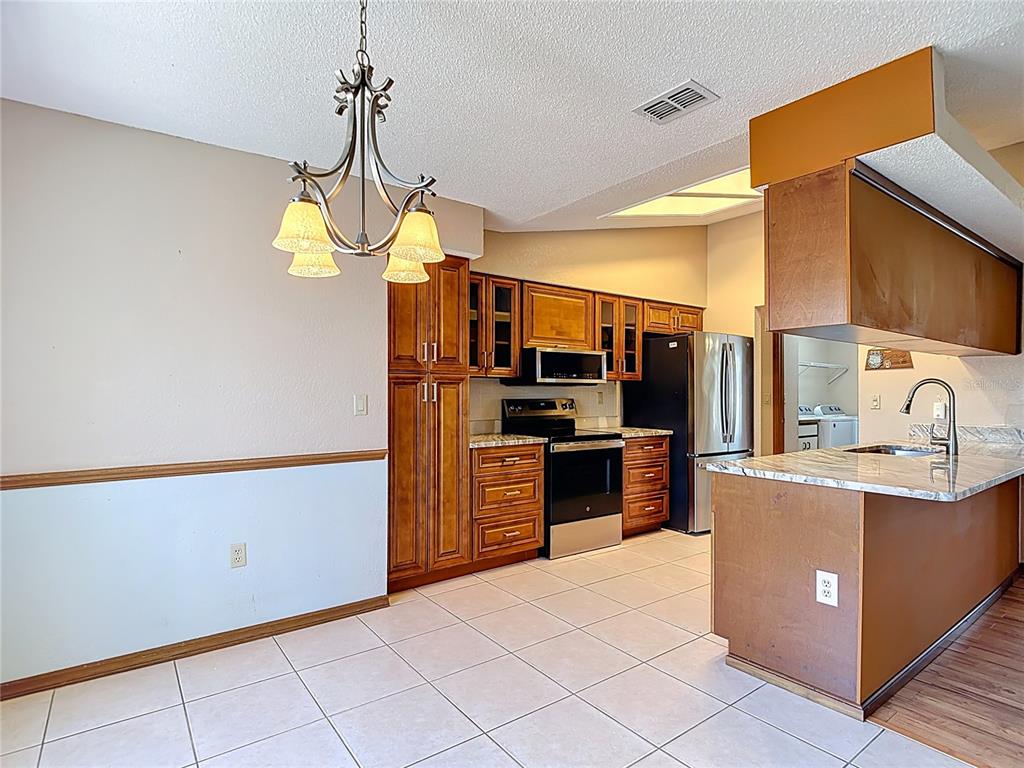 5066 Woodbine Street Spring Hill, FL 34608 - Photo 19 of 59 a kitchen with stainless steel appliances granite countertop a stove cabinets and refrigerator
