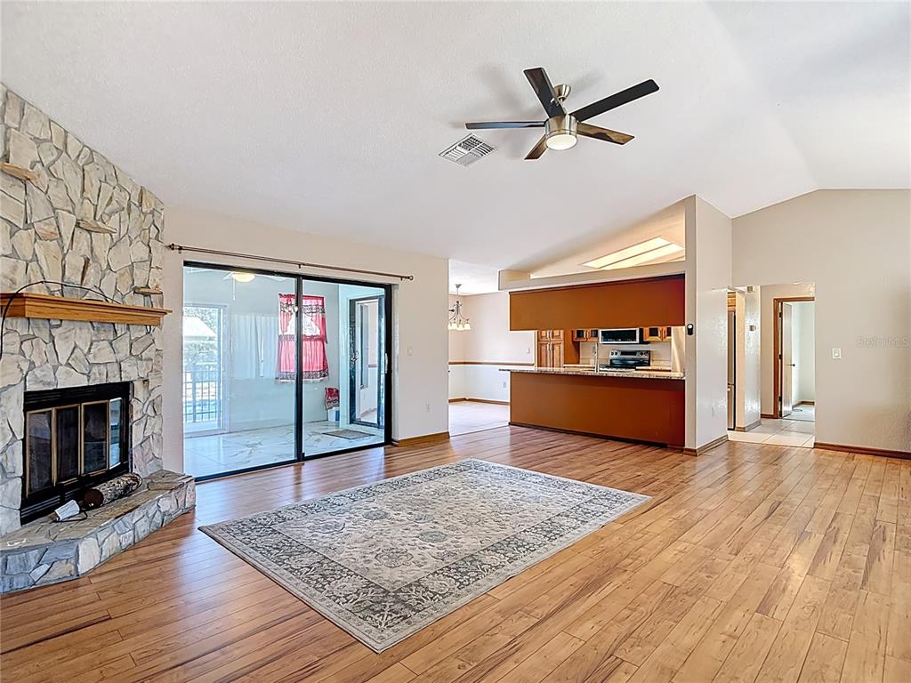 5066 Woodbine Street Spring Hill, FL 34608 - Photo 6 of 59 a living room with wooden floor and a fireplace