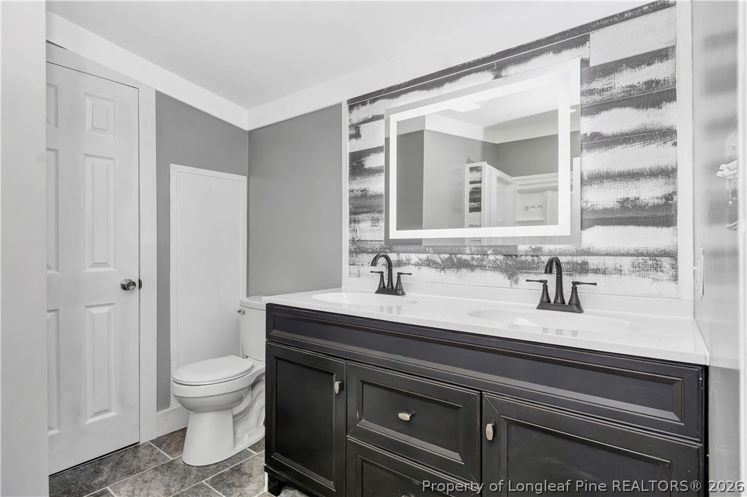 7225 Deep Branch Road Pembroke, NC 28372 - Photo 16 of 27 a bathroom with a granite countertop sink a toilet and a mirror